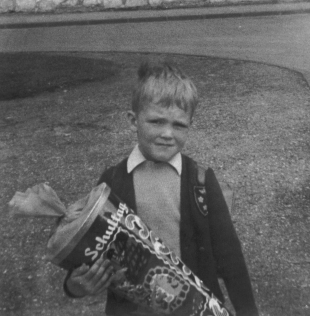 Schwarz-Weiss-Photo von der Sprengerstraße Ecke Struckmannstraße in Hildersheim von einem Jungen an seinem ersten Schultag mit seiner Schultüte.