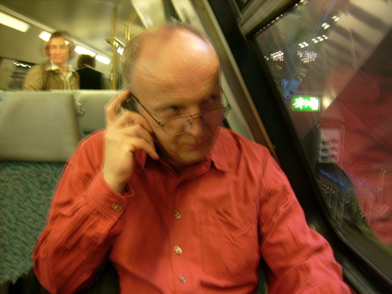 Farbphoto: Erwin Thomasius sitzt in der oberen Etage eines Doppeldeckerwaggons und telephoniert mit seinem Handy. Im Warnemünde-Express im Tiefgeschoss des Berliner Hauptbahnhofs auf Gleis 6 im Juni 2009. Photograph: Bernd Paepcke.