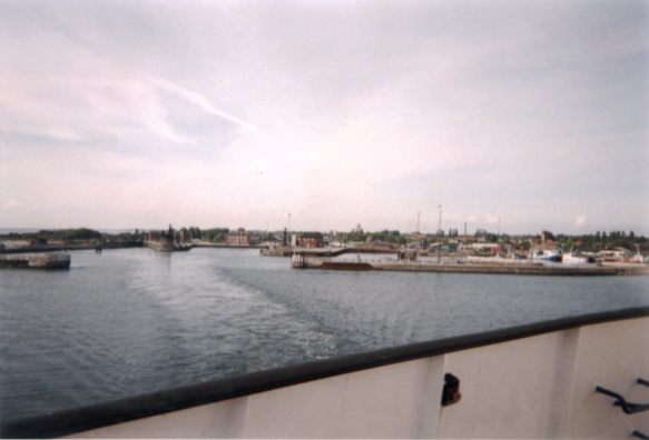 Farbphoto: Blick auf Gedser von der von Gedser Richtung Warnemünde/Rostock fahrenden Fähre aus. Links von der Bildmitte sieht man die Hafenausfahrt von Gedser, durch die die Fähre gerade vom Hafen von Gedser in die Ostsee hinaus hindurchgefahren ist. Mai 2002. Copyright by jen.